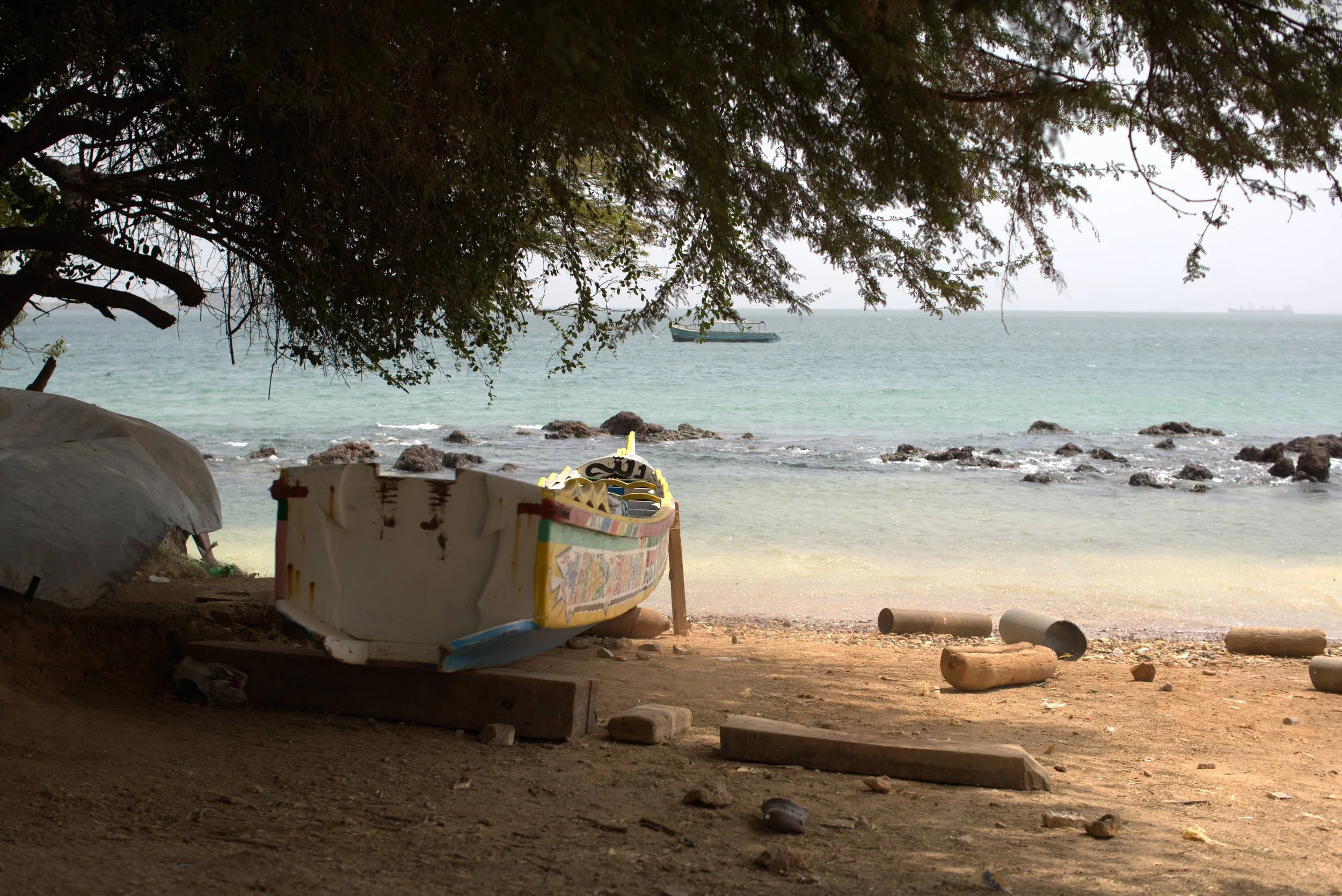 A painted wooden fishing boat drawn up on a beach in Dakar, Senegal, with the Atlantic behind